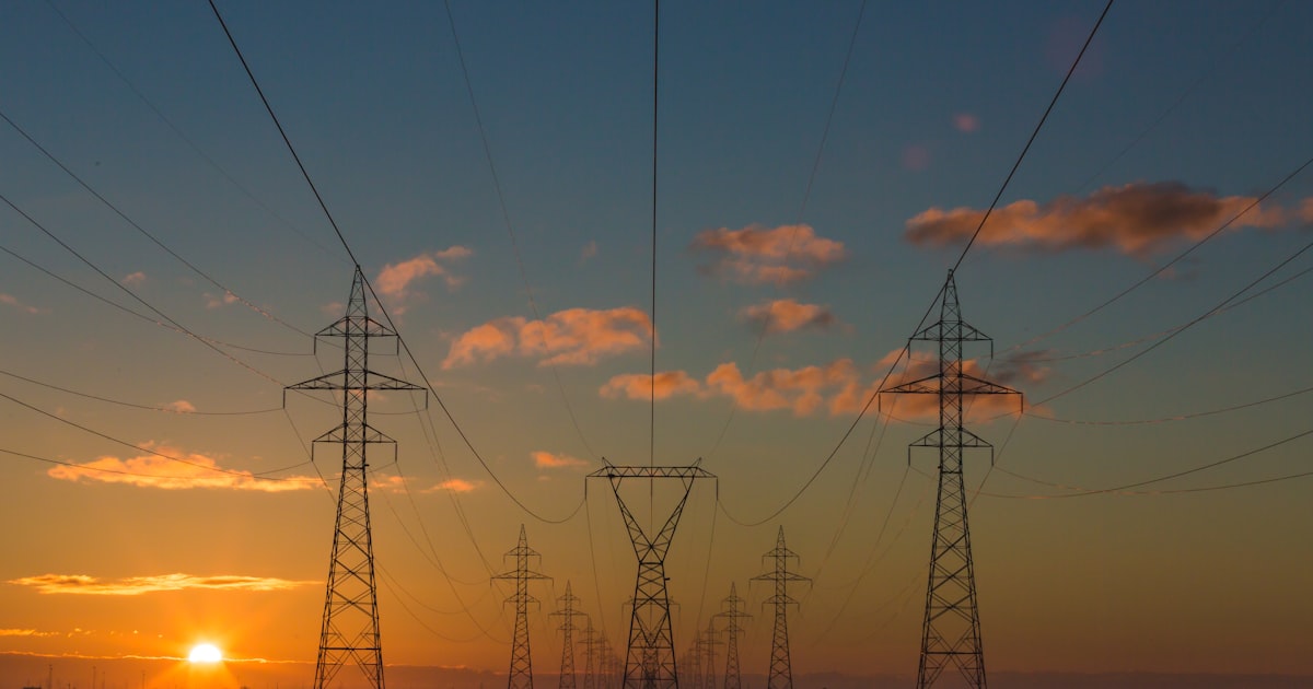 Electricity transmission pylons silhouetted at sunset